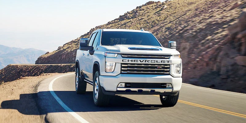 White Chevrolet Silverado driving between mountain roads